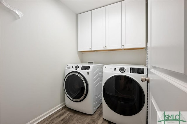 washroom featuring cabinet space, baseboards, washer and dryer, and wood finished floors