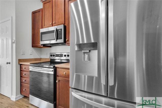 kitchen featuring stainless steel appliances, light wood-type flooring, brown cabinets, and light countertops