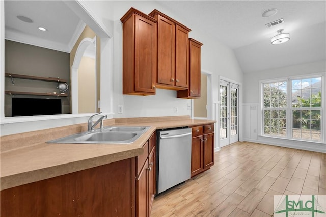 kitchen featuring dishwasher, brown cabinets, vaulted ceiling, light wood-style floors, and a sink