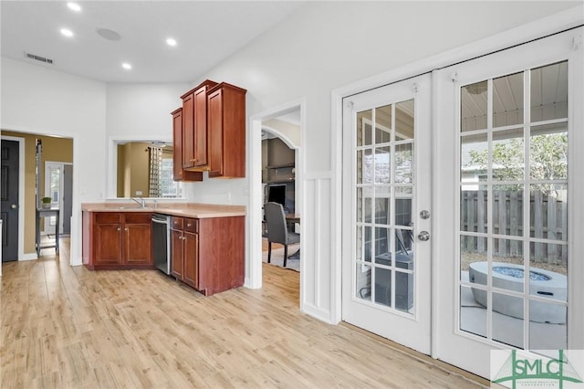 kitchen with arched walkways, visible vents, light countertops, stainless steel dishwasher, and light wood-type flooring