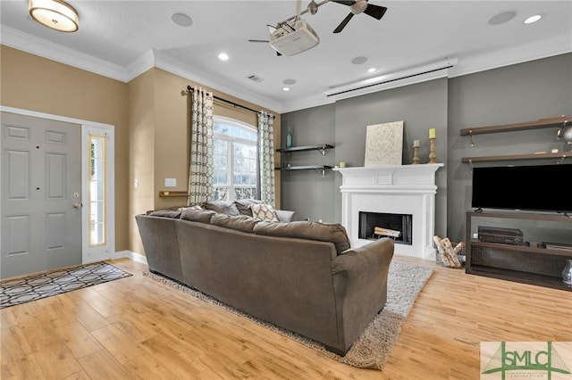 living area featuring recessed lighting, a fireplace, wood finished floors, baseboards, and ornamental molding