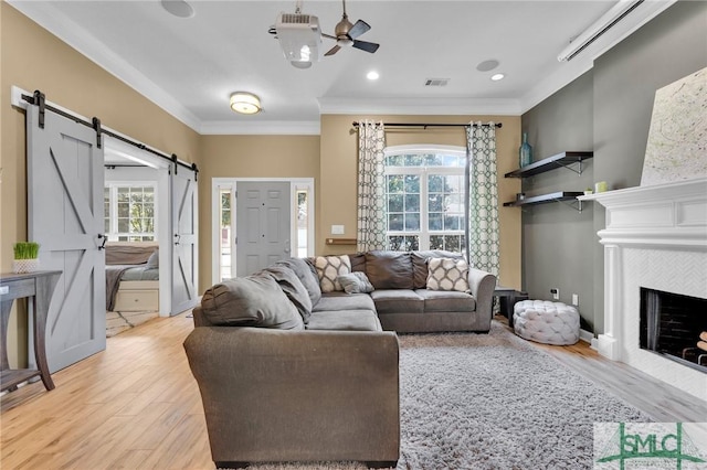 living room featuring ornamental molding, a healthy amount of sunlight, visible vents, and a barn door