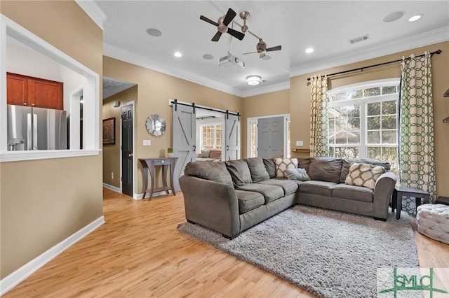 living room featuring ornamental molding, a barn door, and light wood-type flooring