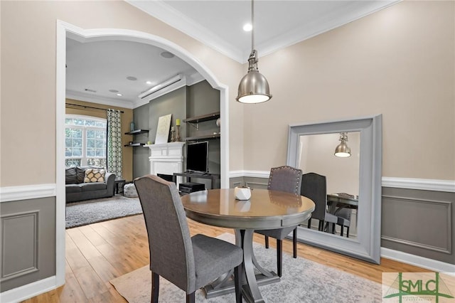 dining space with a wainscoted wall, light wood-style flooring, and crown molding