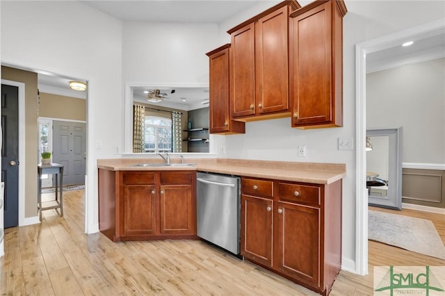 kitchen featuring light countertops, a sink, light wood-style flooring, and stainless steel dishwasher