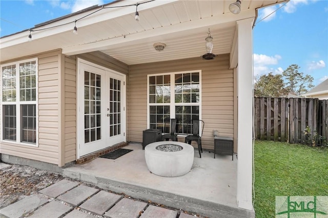 view of patio / terrace featuring an outdoor fire pit, fence, and french doors