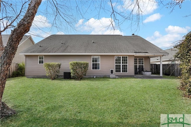 back of house with a patio, a shingled roof, a lawn, and fence