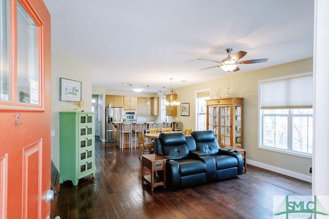 living area featuring dark wood-style floors, baseboards, and ceiling fan with notable chandelier