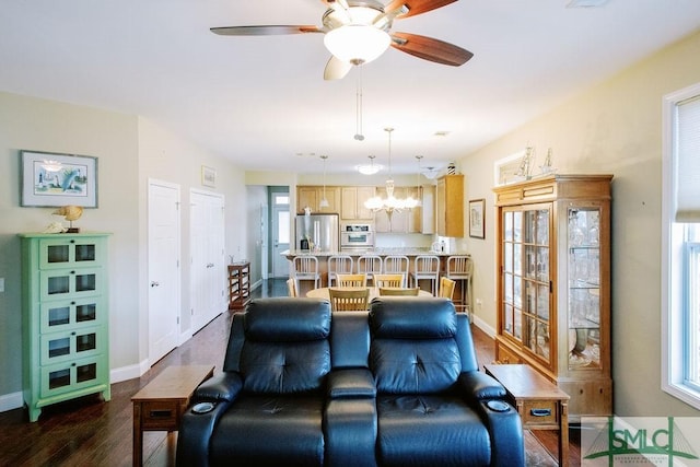 living room with baseboards, dark wood-style flooring, and ceiling fan with notable chandelier