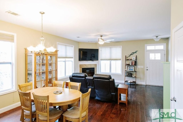 dining area with dark wood finished floors, a glass covered fireplace, visible vents, and baseboards