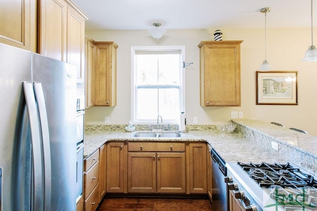 kitchen featuring appliances with stainless steel finishes, a peninsula, light stone countertops, pendant lighting, and a sink