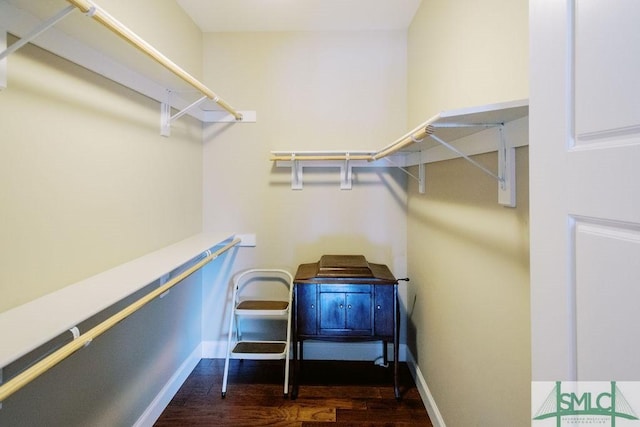 walk in closet with dark wood-type flooring