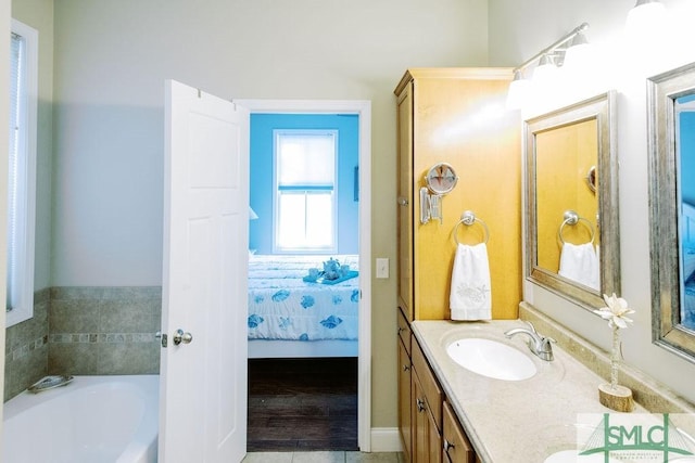 ensuite bathroom with a garden tub, double vanity, a sink, and connected bathroom