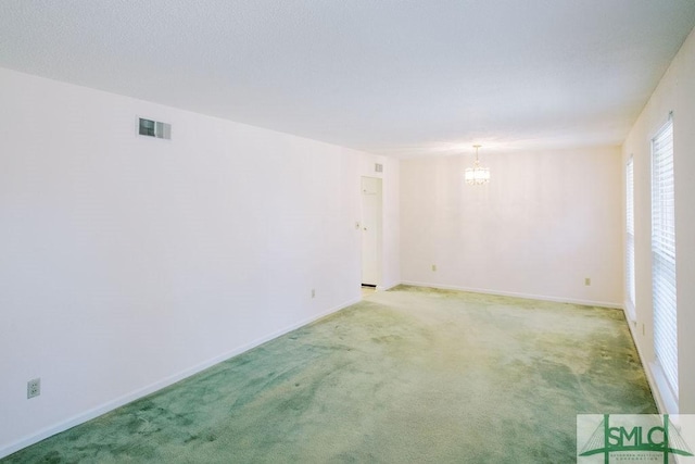 empty room featuring light carpet, a notable chandelier, visible vents, and baseboards