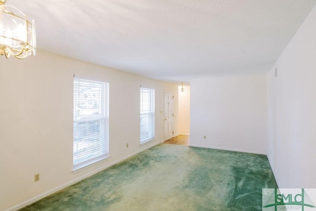 empty room with carpet, a textured ceiling, baseboards, and an inviting chandelier