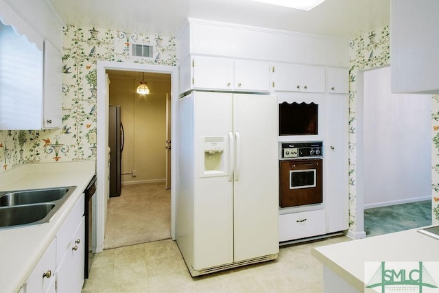 kitchen featuring white refrigerator with ice dispenser, visible vents, wall oven, freestanding refrigerator, and wallpapered walls