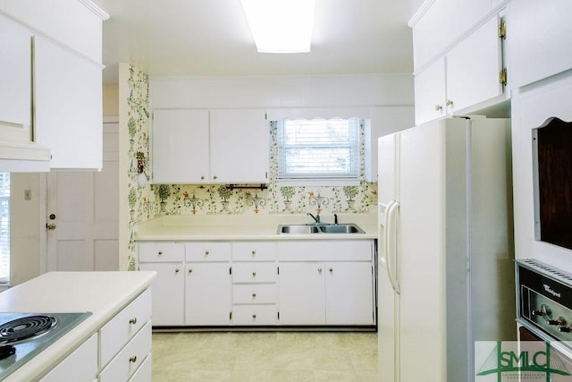 kitchen featuring light countertops, stainless steel electric cooktop, white cabinets, a sink, and white fridge with ice dispenser