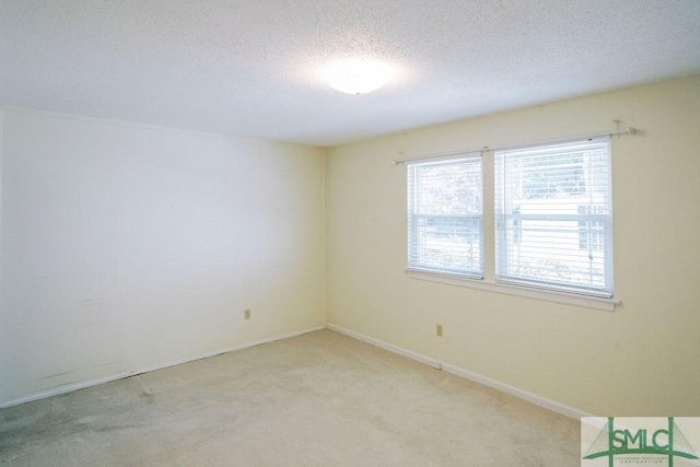 carpeted empty room featuring a textured ceiling and baseboards