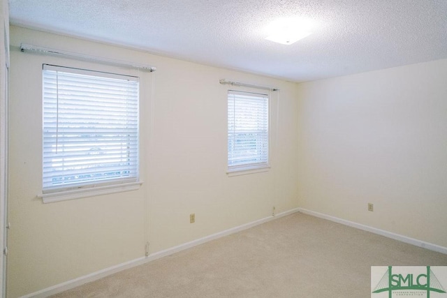 carpeted empty room featuring baseboards and a textured ceiling