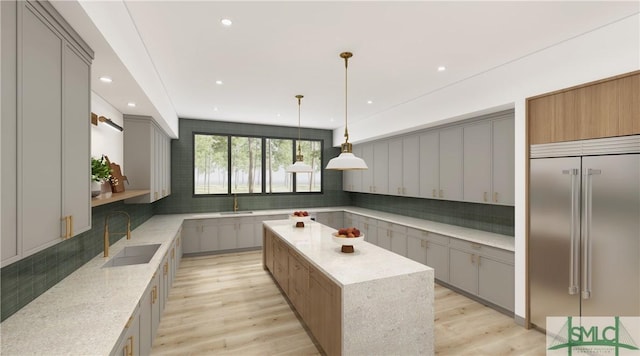 kitchen with light wood finished floors, built in refrigerator, a sink, and gray cabinetry