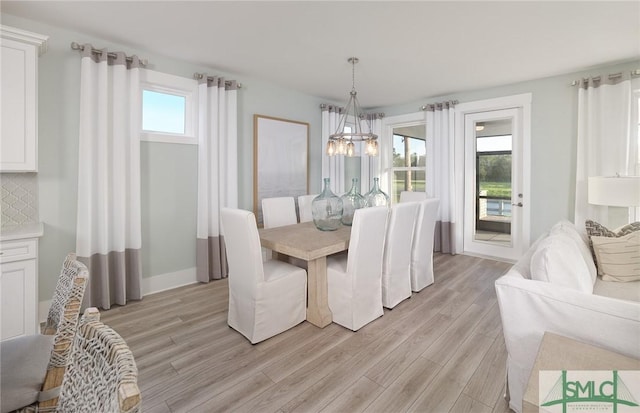 dining space with a chandelier, baseboards, and light wood finished floors