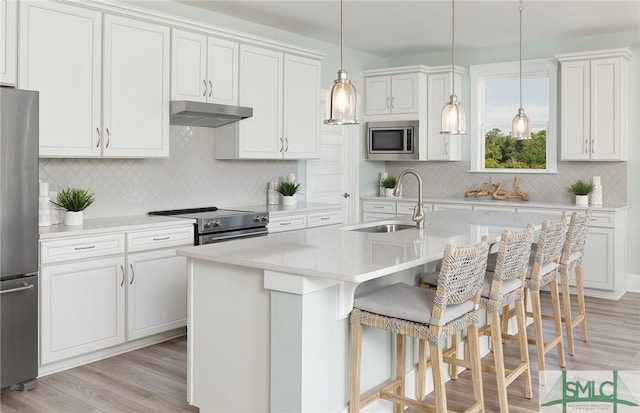 kitchen featuring a kitchen breakfast bar, stainless steel appliances, light countertops, under cabinet range hood, and a sink