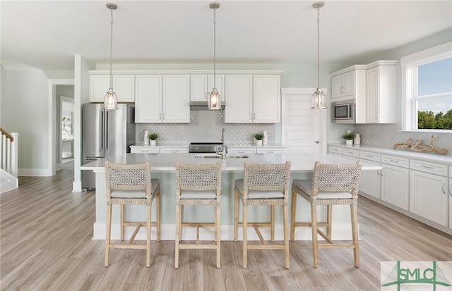 kitchen featuring light wood finished floors, light countertops, appliances with stainless steel finishes, and a sink
