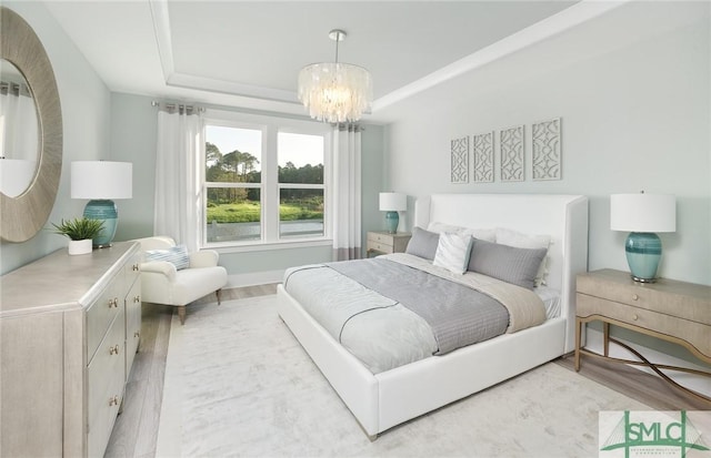 bedroom with a chandelier, a tray ceiling, light wood-type flooring, and baseboards