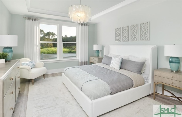 bedroom with a chandelier, wood finished floors, and a raised ceiling
