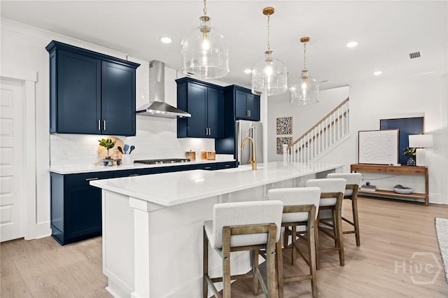 323 Birch Dr, Richmond Hill, GA 31324 - kitchen featuring wall chimney range hood, blue cabinets, light wood-type flooring, gas cooktop, and recessed lighting