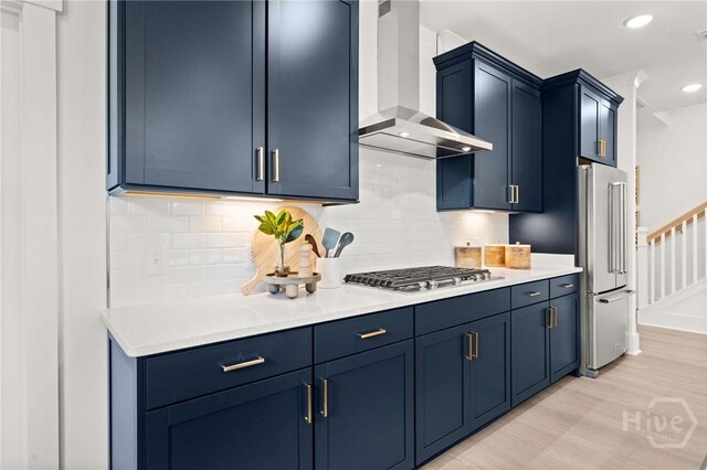 323 Birch Dr, Richmond Hill, GA 31324 - kitchen with wall chimney exhaust hood, appliances with stainless steel finishes, blue cabinetry, and recessed lighting