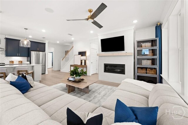 323 Birch Dr, Richmond Hill, GA 31324 - living area featuring light wood finished floors, recessed lighting, ceiling fan, stairway, and a glass covered fireplace