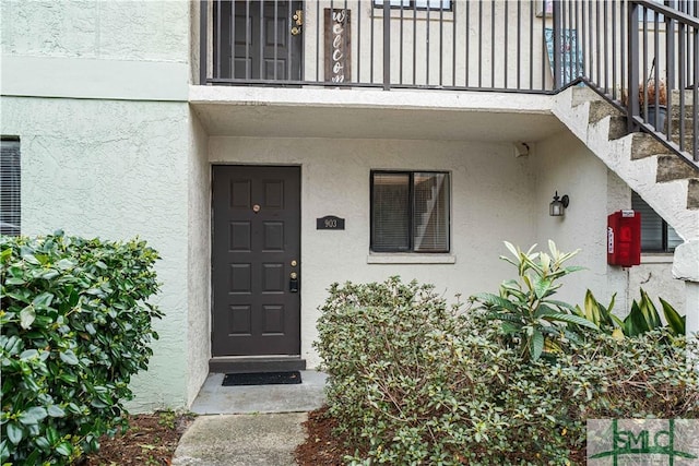 doorway to property with a balcony and stucco siding