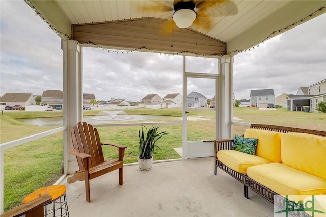 sunroom with ceiling fan, a residential view, and vaulted ceiling