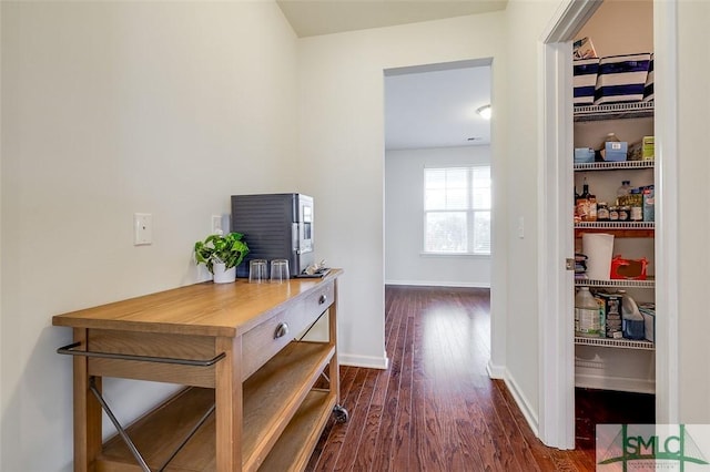 corridor with baseboards and wood finished floors