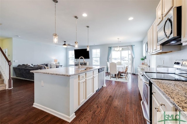 kitchen featuring a center island with sink, open floor plan, dark wood-type flooring, stainless steel appliances, and a sink