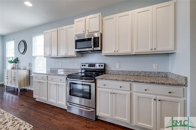 kitchen featuring appliances with stainless steel finishes, white cabinetry, dark wood finished floors, and light stone countertops