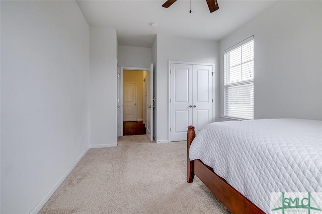 bedroom with light carpet, ceiling fan, a closet, and baseboards