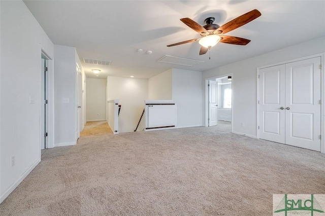 unfurnished room featuring carpet floors, attic access, visible vents, and baseboards