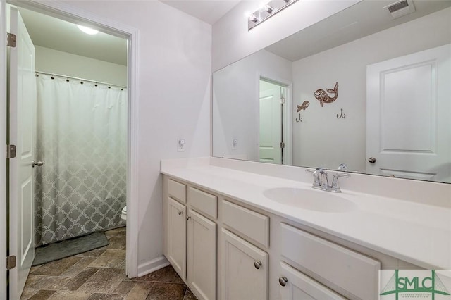 bathroom with visible vents, baseboards, toilet, stone finish flooring, and vanity