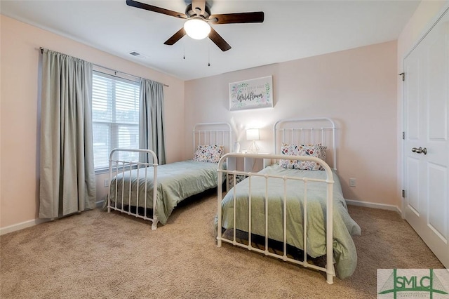 carpeted bedroom featuring a ceiling fan, visible vents, and baseboards