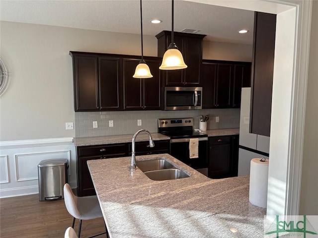 119 Sams Dr, Guyton, GA 31312 - kitchen with appliances with stainless steel finishes, a sink, dark brown cabinetry, wainscoting, and hanging light fixtures