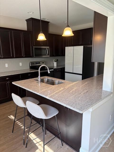 119 Sams Dr, Guyton, GA 31312 - kitchen featuring stainless steel appliances, a sink, light stone countertops, and a breakfast bar