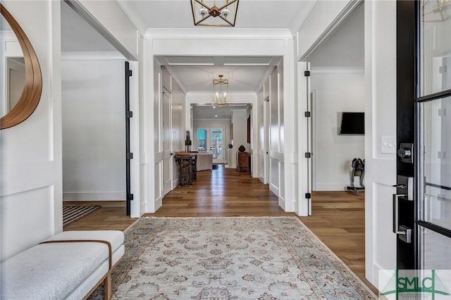 entryway with a chandelier, crown molding, and wood finished floors