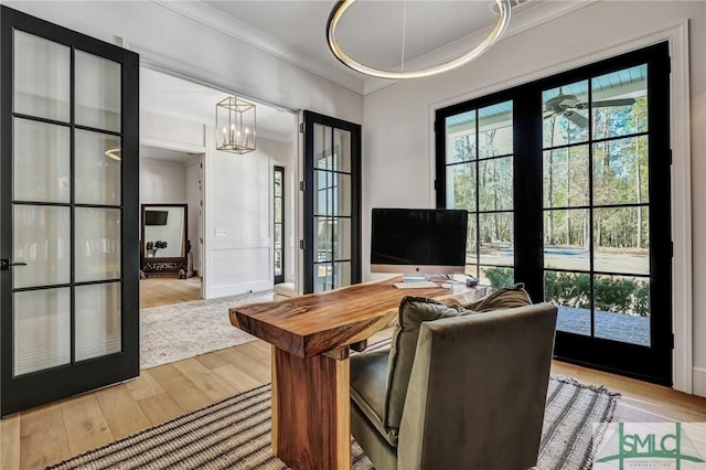 home office featuring a wealth of natural light, an inviting chandelier, wood finished floors, and french doors