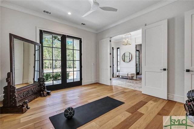 workout area with ornamental molding, baseboards, visible vents, and light wood finished floors