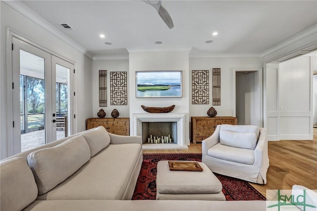 living room with a fireplace, crown molding, recessed lighting, ceiling fan, and light wood-type flooring