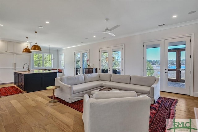 living area featuring french doors, recessed lighting, light wood-style flooring, ornamental molding, and ceiling fan