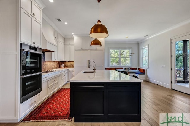 kitchen featuring stainless steel double oven, gas cooktop, a sink, white cabinetry, and ornamental molding