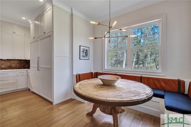 dining room featuring breakfast area, crown molding, light wood-type flooring, a notable chandelier, and recessed lighting